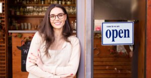 small business owner leaning on the door beside an open sign