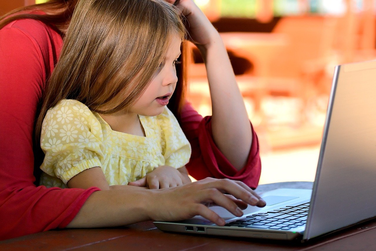 child on mothers lap looking at a laptop child on mothers lap looking at a laptop