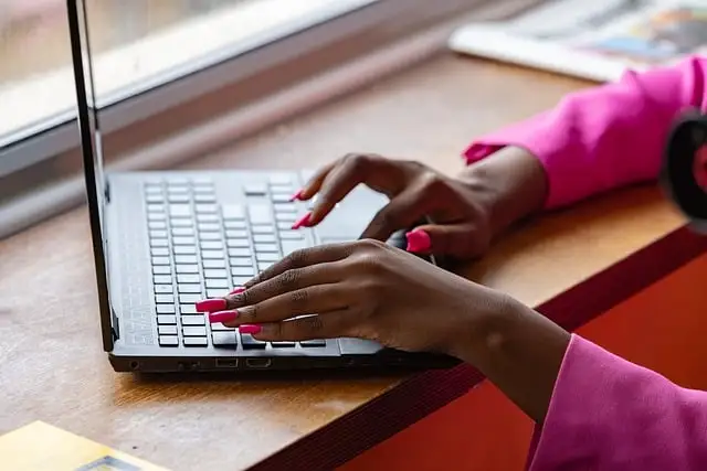 a woman inputs data into a billing software on a laptop