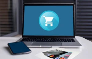 ecommerce shopping cart on laptop with credit cards and mobile phone beside it