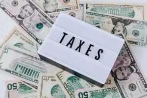 payroll taxes shown as money on a table with a plaque with taxes written on it
