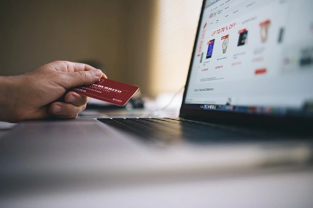 payment processing for ecommerce site with person holding a credit card infront of a laptop