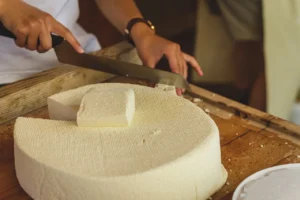 Cheese maker working with a raw block of cheese
