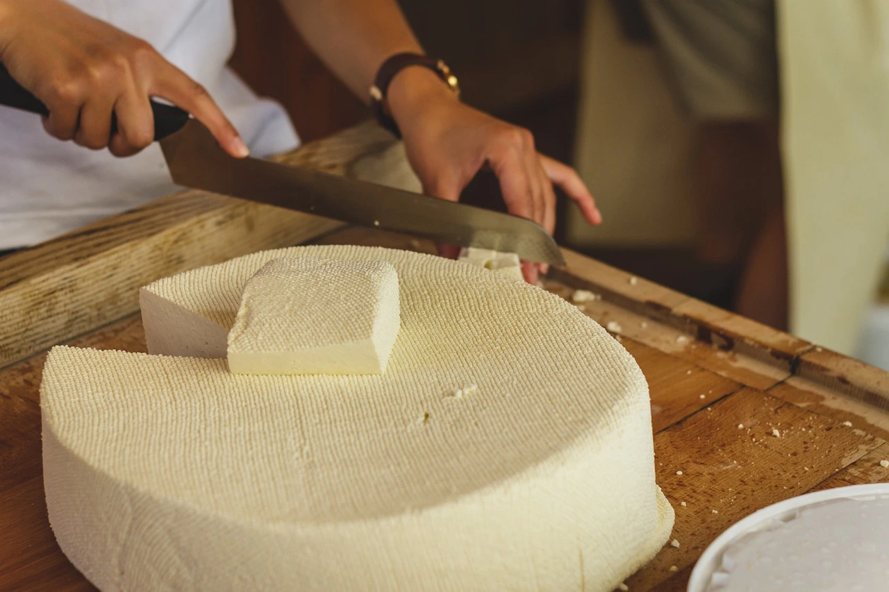 Cheese-maker-working-with-a-raw-block-of-cheese Cheese maker working with a raw block of cheese