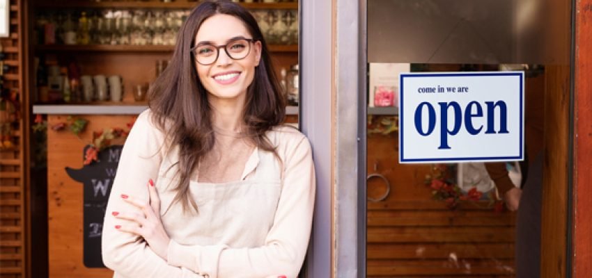 small business owner leaning on the door beside an open sign