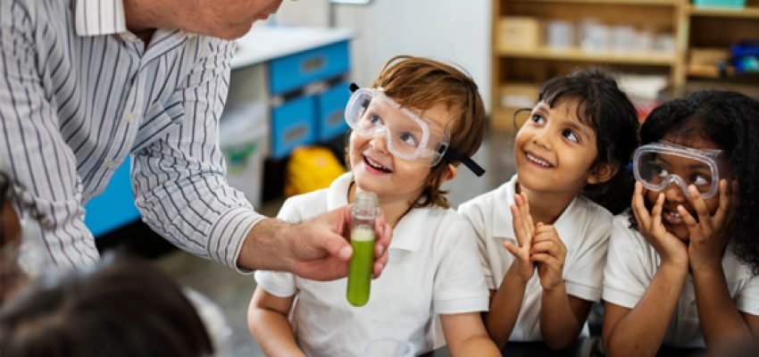 Educator teaching young students via a science experiment