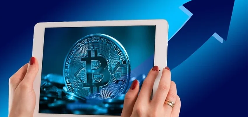 bitcoin shown on a mobile tablet and a graph behind showing growth