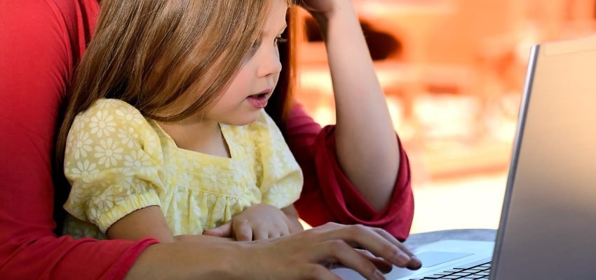child on mothers lap looking at a laptop