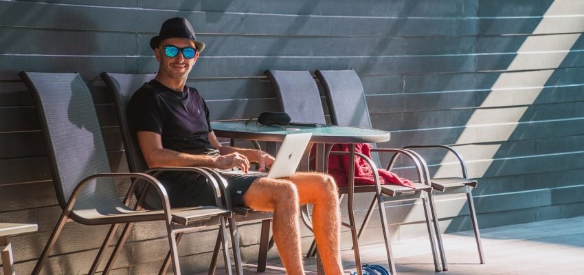 man sitting on a chair by the pool with his laptop