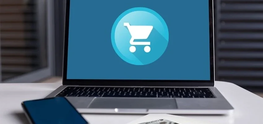 ecommerce shopping cart on laptop with credit cards and mobile phone beside it