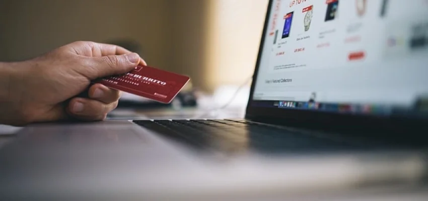 payment processing for ecommerce site with person holding a credit card infront of a laptop