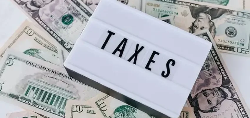 payroll taxes shown as money on a table with a plaque with taxes written on it