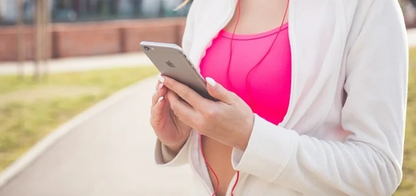 woman checking Fitness App during her run outdoors